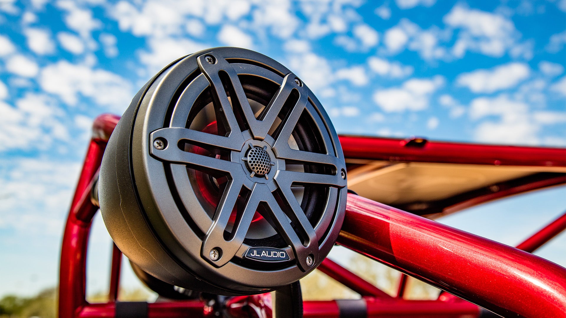 A gunmetal VeX unit on a red framed powersports vehicle with a bright blue sky background.