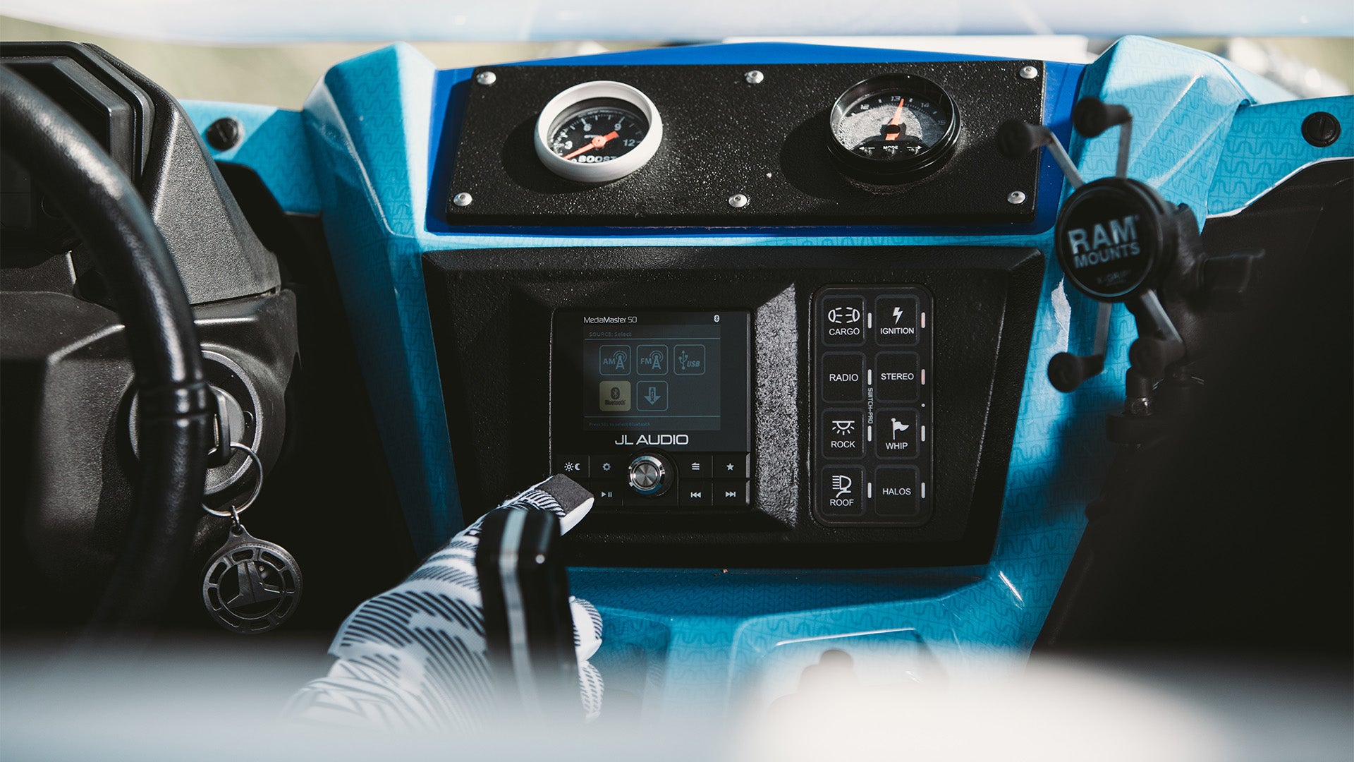A drivers finger pressing the button to a MediaMaster source unit inside a powersports vehicle.
