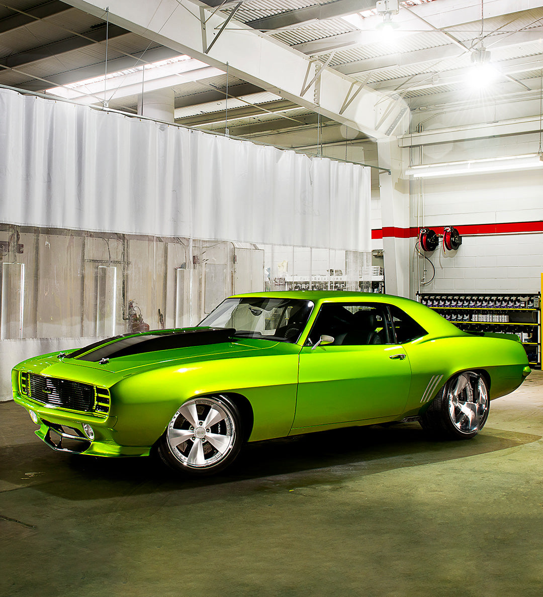 A lime green muscle car parked in a garage.