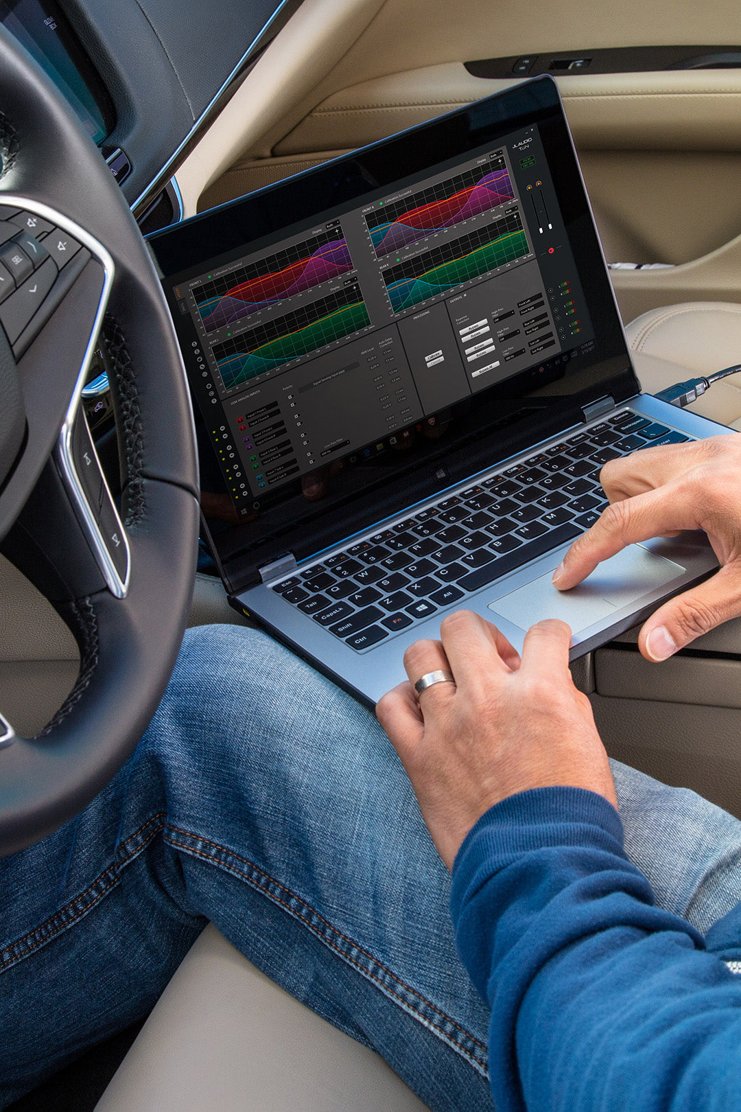 A person inside a vehicle adjusting sound frequencies using TuN software on a laptop.