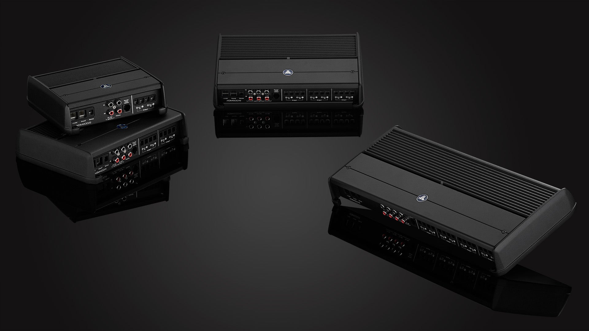 A set of 4 XDM amplifiers in a dark sleek setting.