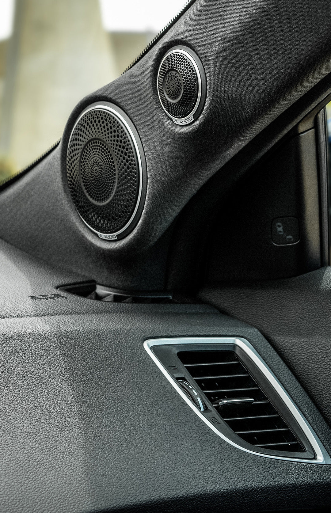 A pair of car audio speakers installed in a sedan.