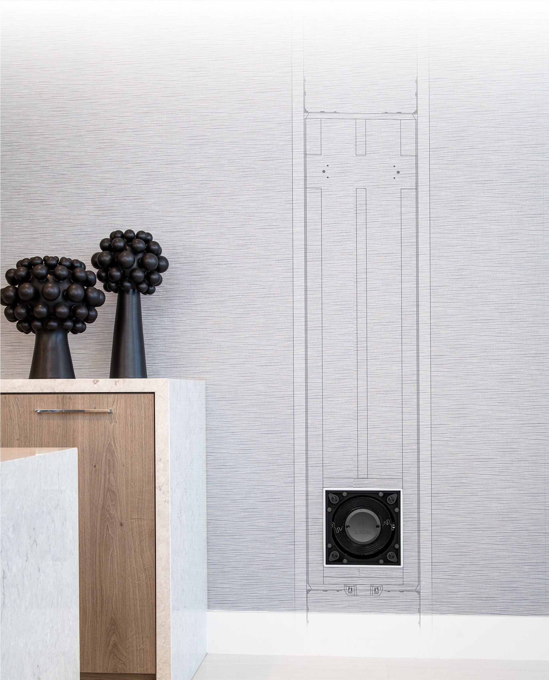 Fathom IWS-8 subwoofer in a home setting with schematic sketch of placement on wall.